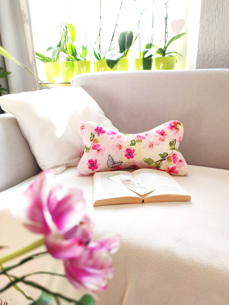 Leseknochen mit pinken Blüten auf Sofa