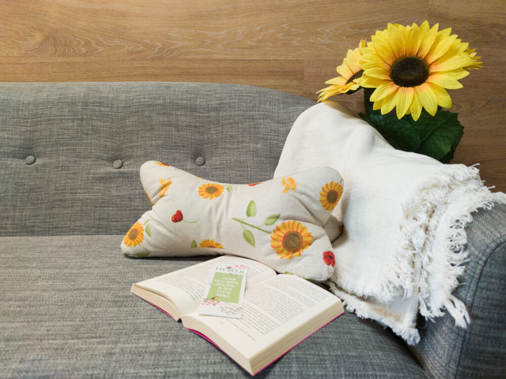 Leseknochen Sonnenblume und Buch liegen auf einem Sofa