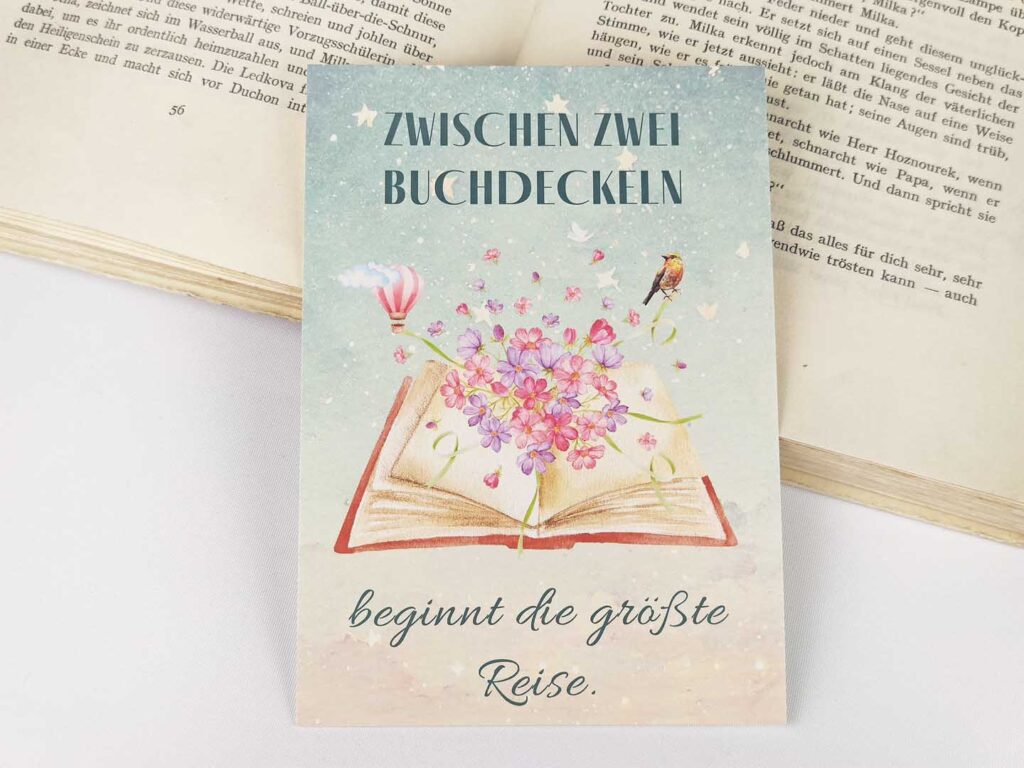 Postkarte mit Spruch „Zwischen zwei Buchdeckeln beginnt die größte Reise.“ (Hochformat)