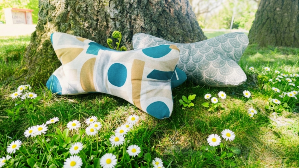 Leseknochen mit Kissen im Garten unter Baum mit Gänseblümchen